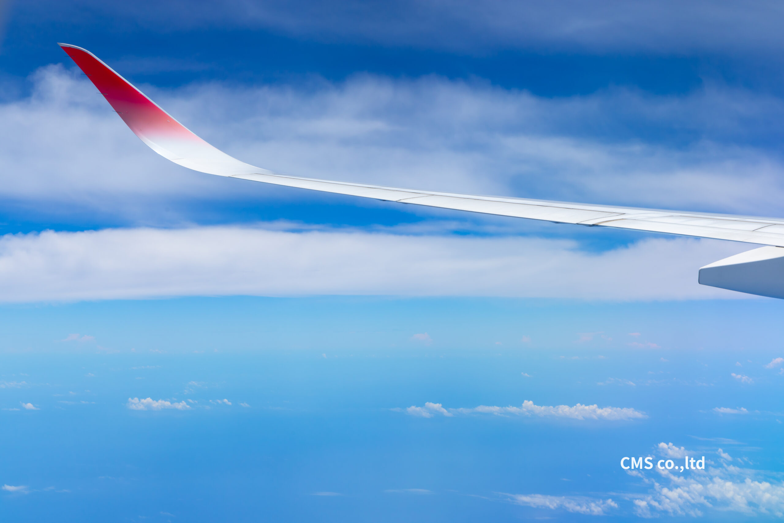 旅客機の窓から撮影された美しく澄み切った青空と白い雲海、航空機の主翼（千葉県千葉市のハイクオリティな映像会社 CMS株式会社撮影の航空・青空写真）
