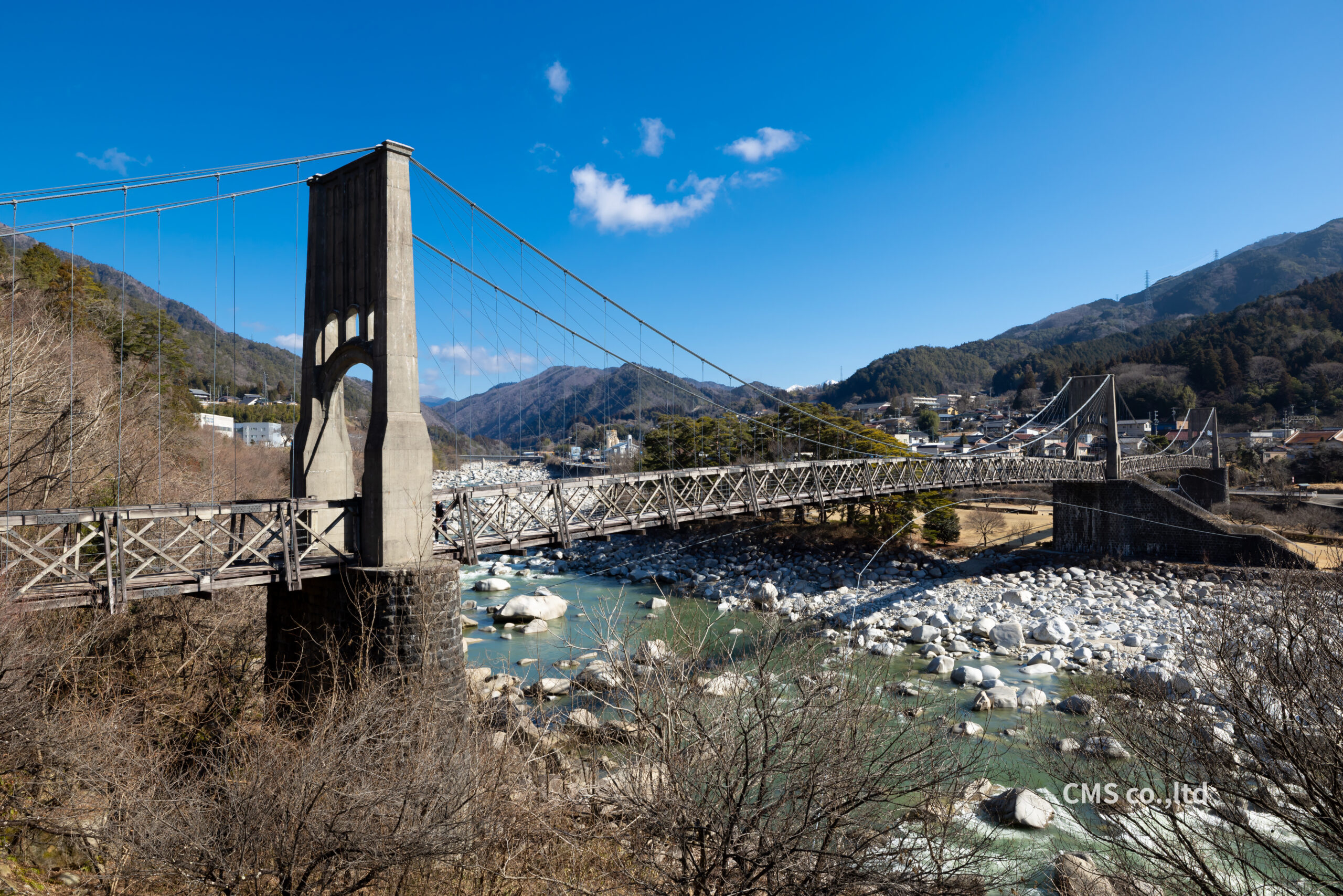 岩がちな川床にそびえ立つ桃介橋のコンクリート主塔と木製トラスの風景